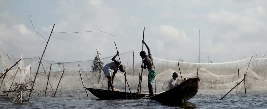 Zwei Fischer mit Stöcken und Booten auf dem Wasser