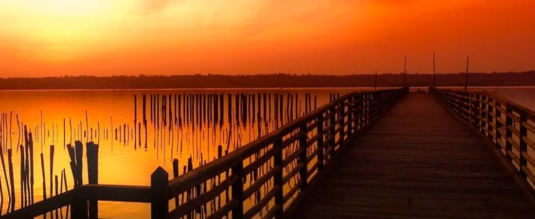 Steg zu einem See beim Sonnenuntergang